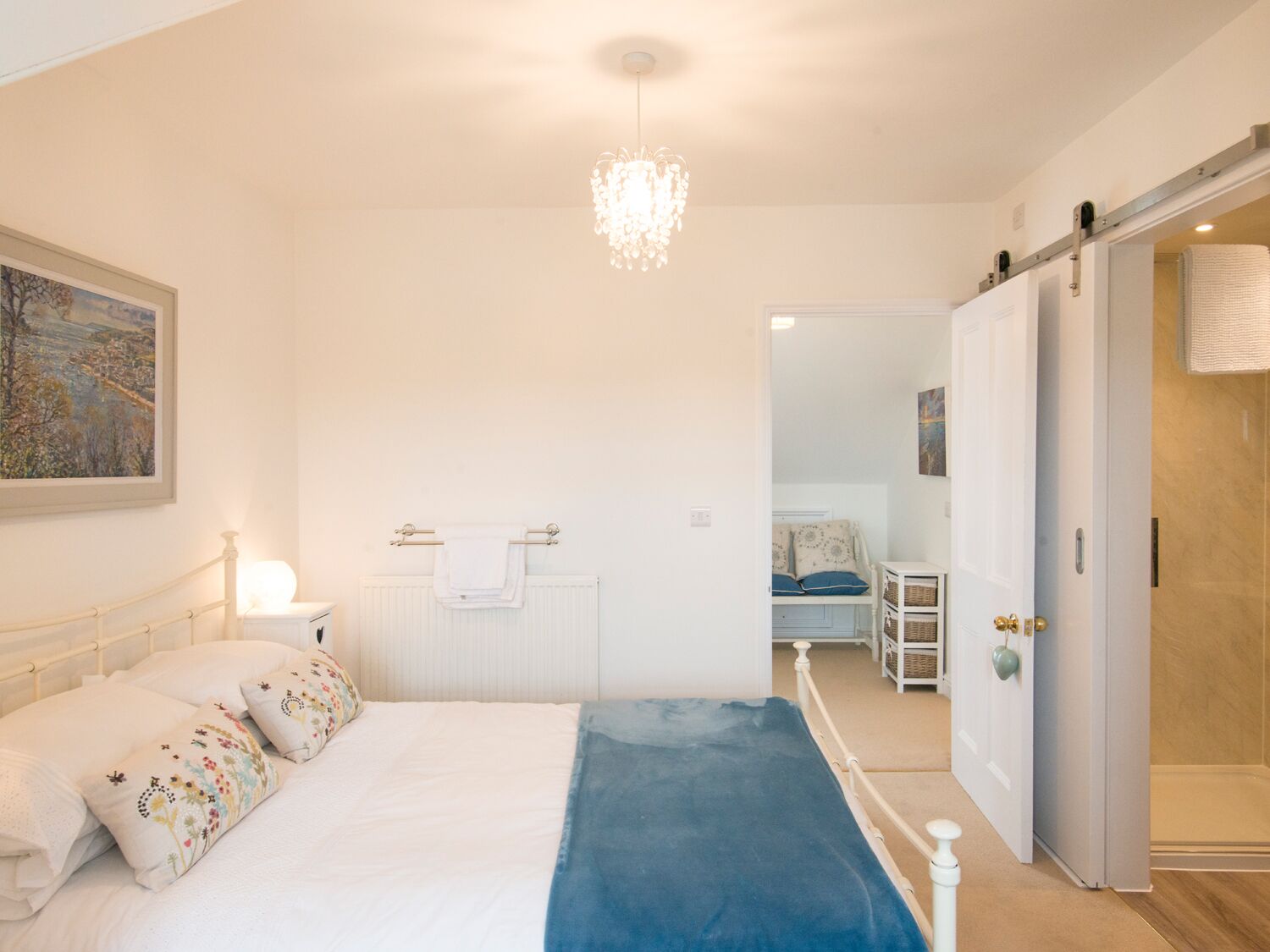 Une chambre à coucher comprenant un lit, un radiateur, un luminaire suspendu et une armoire.