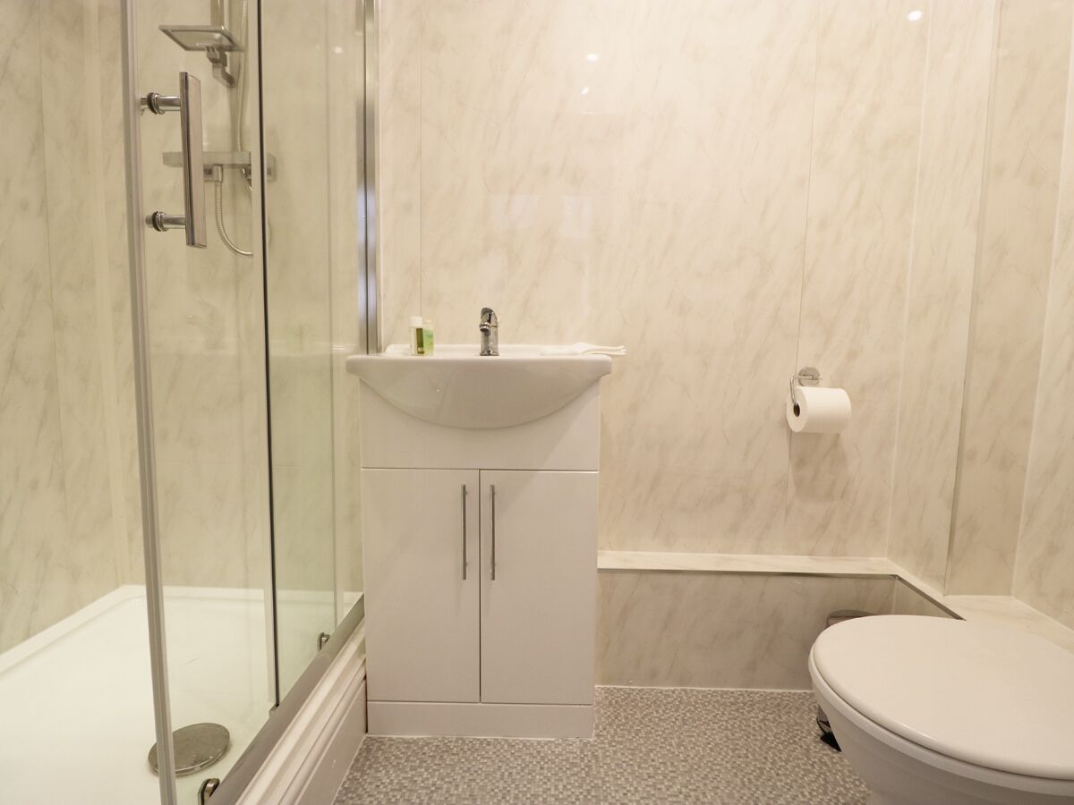 A bathroom with a glass shower enclosure, a white sink with a mirror, and a toilet.