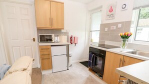 Una cocina compacta con microondas, horno y pileta. Hay un refrigerador pequeño, muebles de madera y un ventanal con vistas.