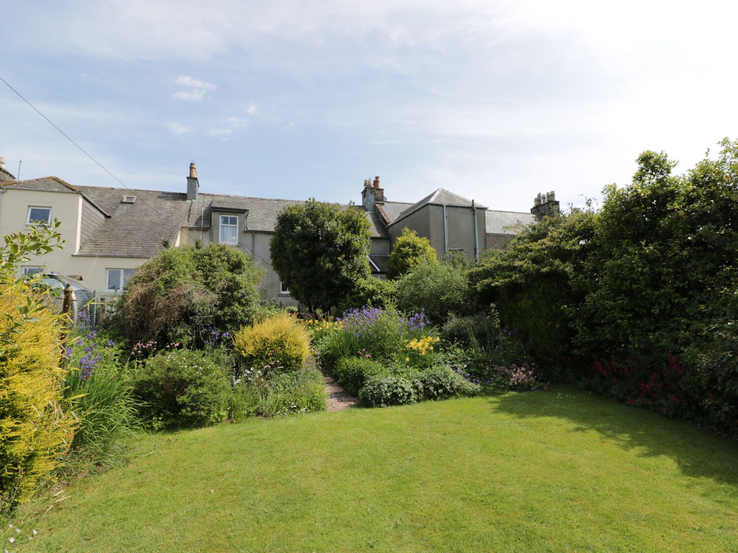 A residential area with houses, a well-maintained lawn, and various flowering plants.