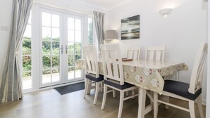 Een eethoek met een tafel en stoelen, een uitzicht door een glazen deur en een lamp aan de muur.