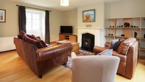 A living room with leather sofas, a television, a fireplace, and a bookshelf. - Dunnottar Woods House (Stonehaven)