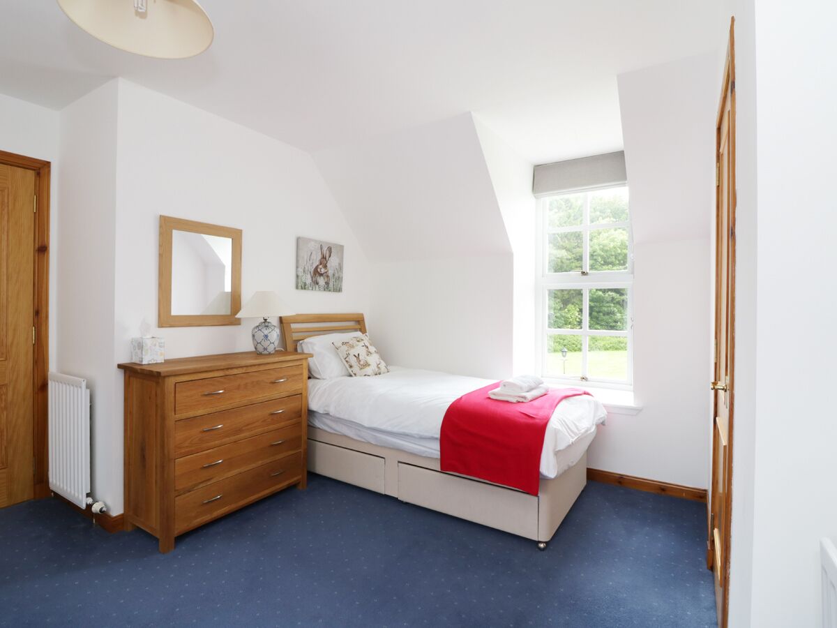 A bedroom with a bed, dresser, mirror, and window.