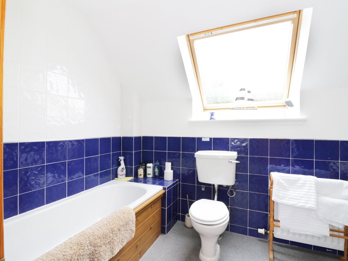 Een badkamer met bad, toilet en wastafel, betegeld met blauwe en witte tegels.