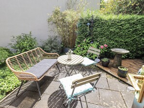 A patio with wicker furniture, a small round table, and potted plants. - Doe Foot Cottage (Carnforth)