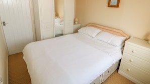 A bedroom with a bed, a nightstand, a dresser, a wardrobe, and a framed picture on the wall. - Surf (Hunstanton)