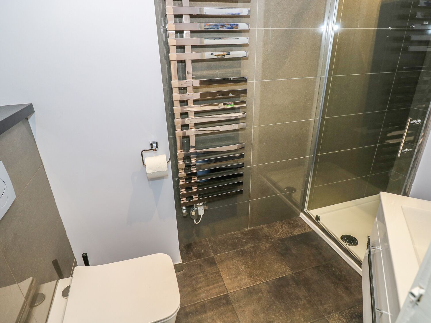 A bathroom with a toilet, a shower, and a glass-enclosed shower stall.