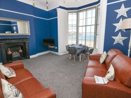 Una habitación con pared azul, chimenea, televisor, mesa de comedor con sillas y sofá de cuero.