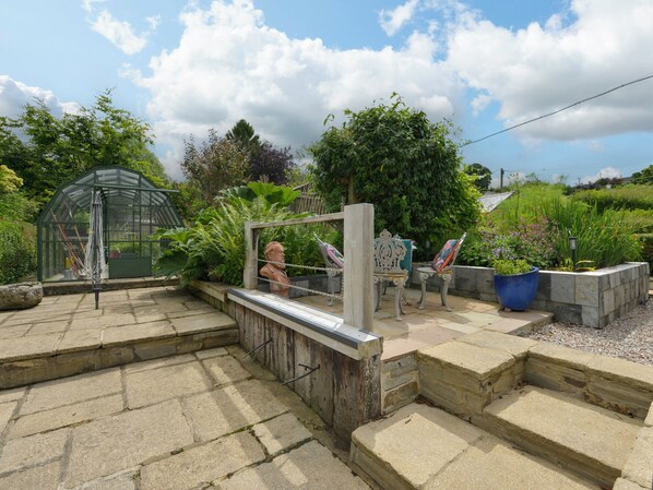 A garden with a greenhouse, stone steps, and a sculpture. - 11 The Village (Yelverton)