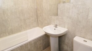 A bathroom with a bathtub, a sink, and a toilet. - The Hen House (Thornton-Cleveleys)
