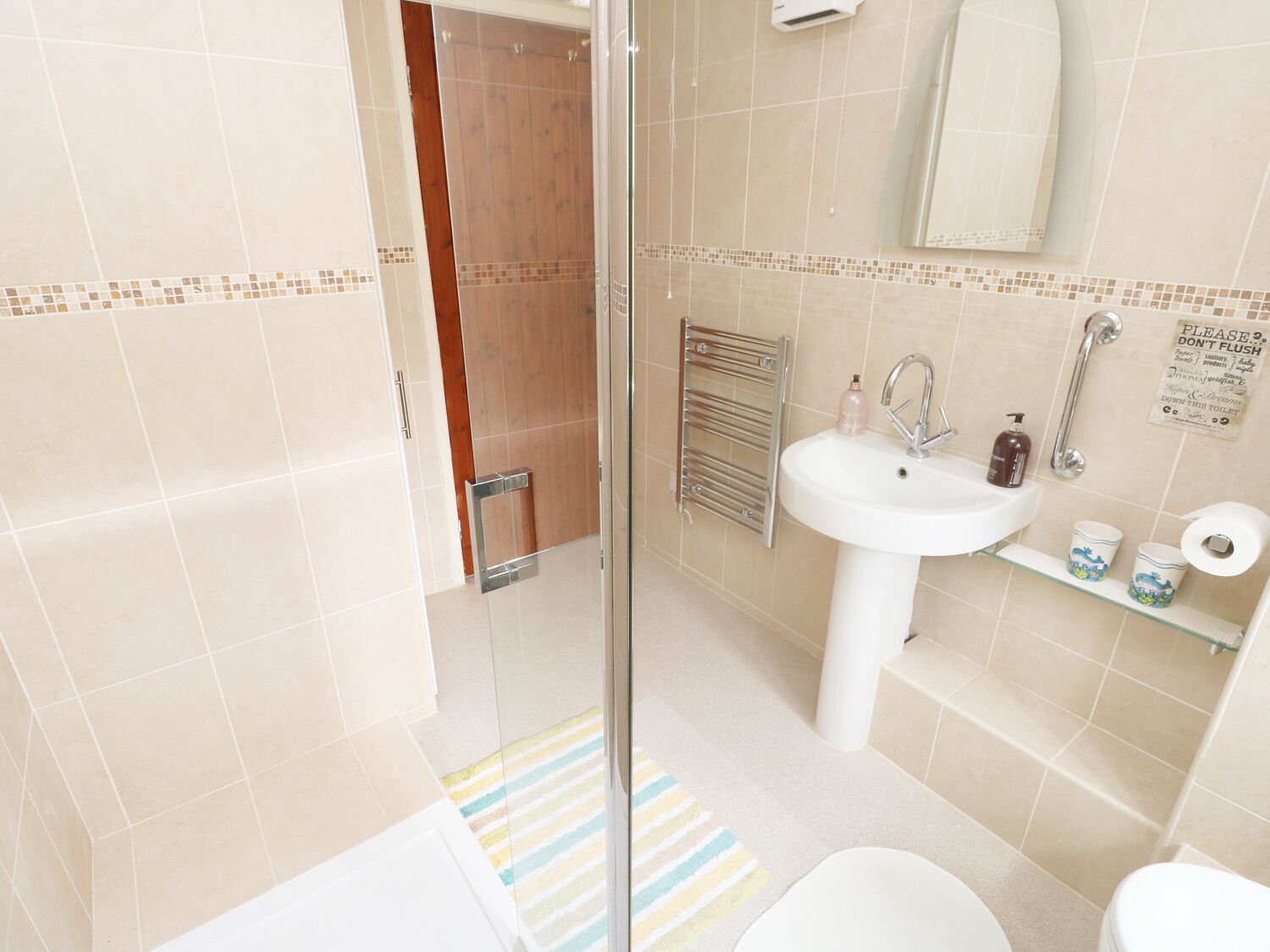 Un baño con cabina de ducha de vidrio, un lavabo blanco, un espejo y un inodoro.