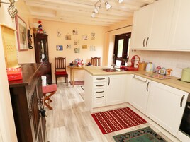 Una cocina con armarios blancos, encimera de madera y alfombra a rayas rojas.