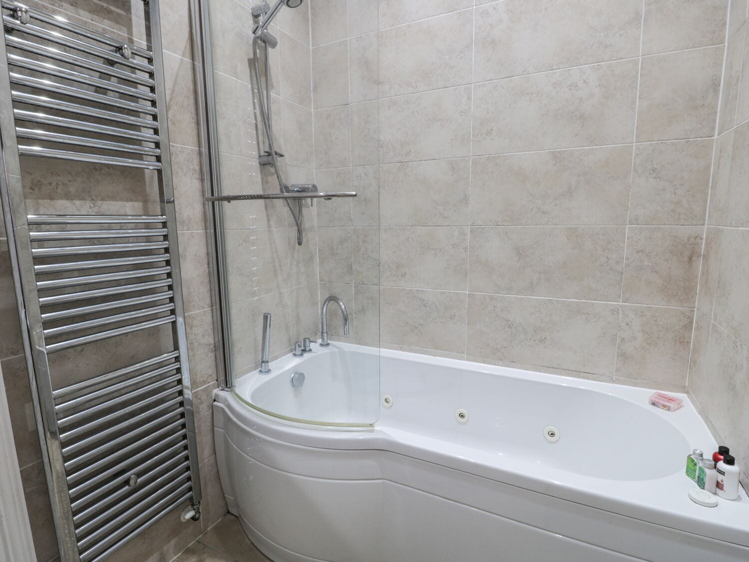 A bathroom with a bathtub, a shower, and a towel rack.