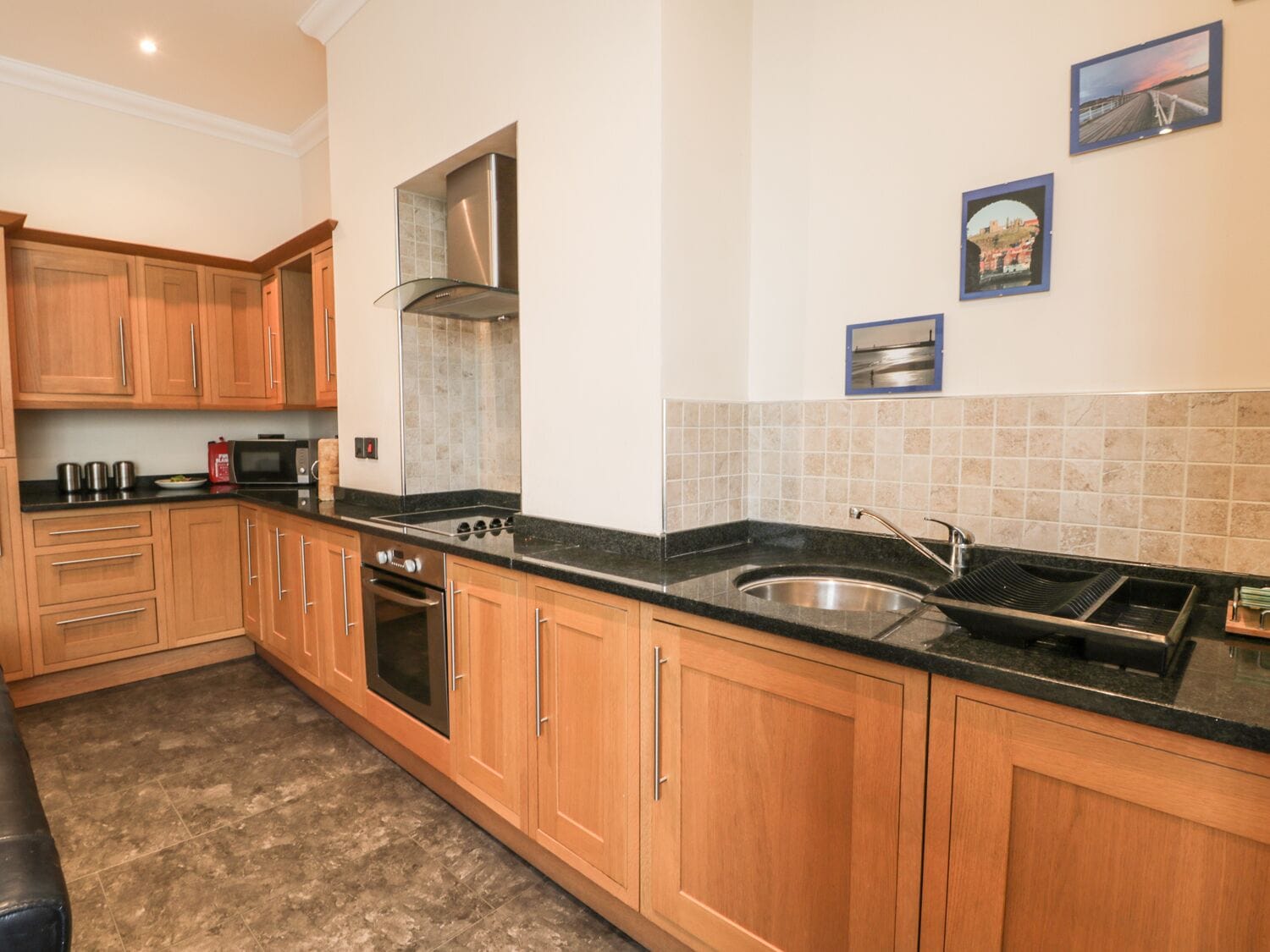 A kitchen with wooden cabinets, a stainless steel sink, and a microwave.
