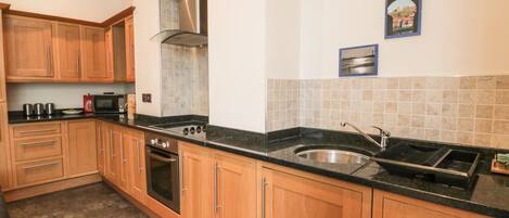 A kitchen with wooden cabinets, a stainless steel sink, and a microwave.