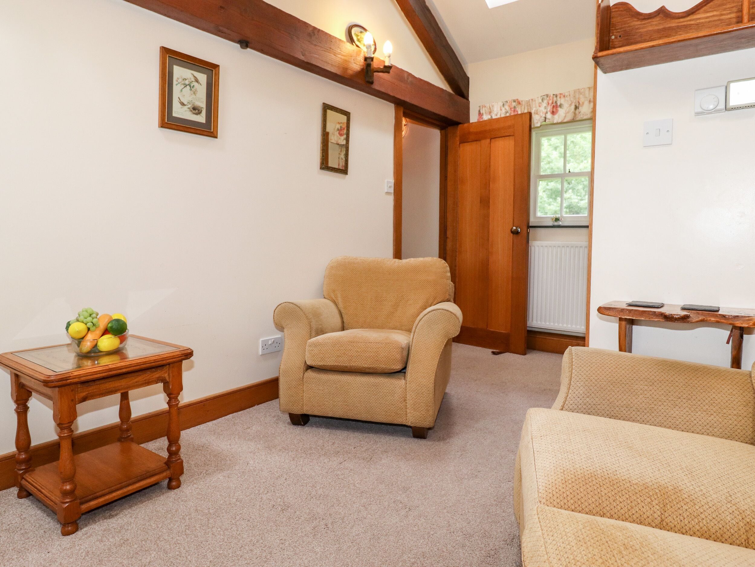 A cozy living room with a beige armchair, a wooden side table with fruit, and a small table with two smartphones.