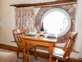 A wooden dining table with chairs, a wine bottle, and a glass.