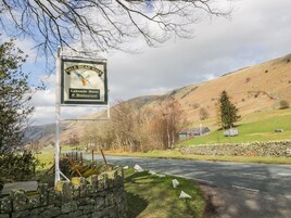 A sign for Dale Head Hall Lakeside Hotel & Restaurant with a scenic view of hills and a stone wall.
