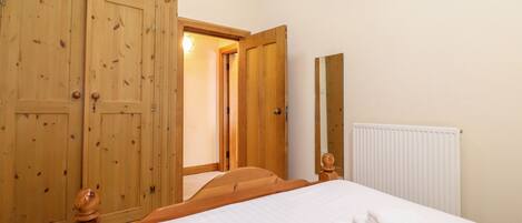 Un dormitorio con una cama grande, un armario de madera y un espejo.