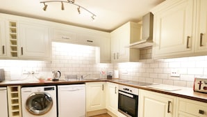 Una cocina moderna con muebles blancos, lavadora, lavavajillas, horno y tostadora.