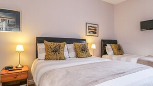 Une chambre d’hôtel avec deux lits, chacun doté d’une tête de lit, d’une table de chevet avec une lampe et d’un tableau au mur.