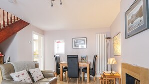 Un salon avec un canapé, une table à manger et des chaises, une cheminée et un escalier.