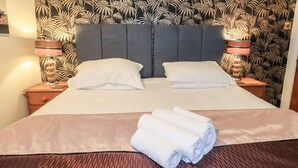 A neatly made bed with white linens, two pillows, and a folded towel on a wooden bed frame. - Granary Nook (Windermere)
