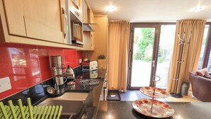 A modern kitchen with a black countertop, a coffee machine, a toaster, and a sink. - Stonegarth Mews (Ambleside)