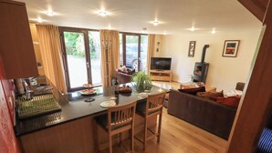 A compact kitchen with a dining area, a TV, and a fireplace. - Stonegarth Mews (Ambleside)