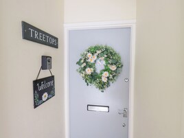 Uma porta com placa de boas-vindas e um arranjo de porta com uma plaquinha.
