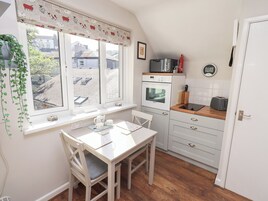 Uma cozinha compacta com mesa de jantar, armários brancos, micro-ondas e torradeira.