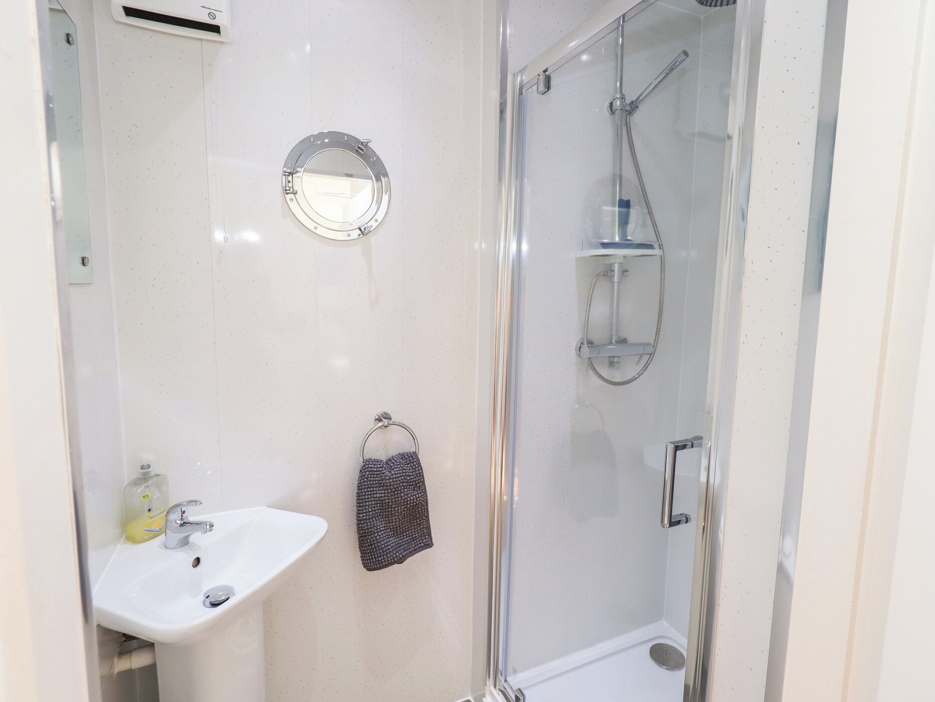 A bathroom with a sink, mirror, and glass shower enclosure.