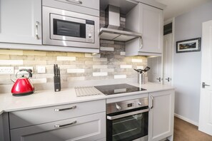 Uma cozinha moderna com micro-ondas, forno e chaleira sobre a bancada.