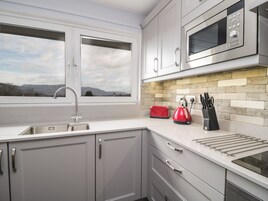 A modern kitchen with a stainless steel sink, a red toaster, and a kettle.