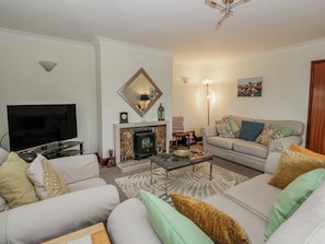 A living room with a flat-screen TV, a fireplace, a sofa, and a coffee table.