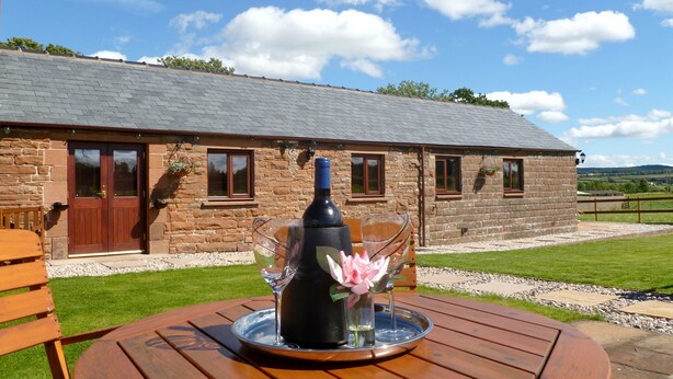 A stone building with a sloped roof, a wooden door, and windows. - Daisy Cottage (Penrith)