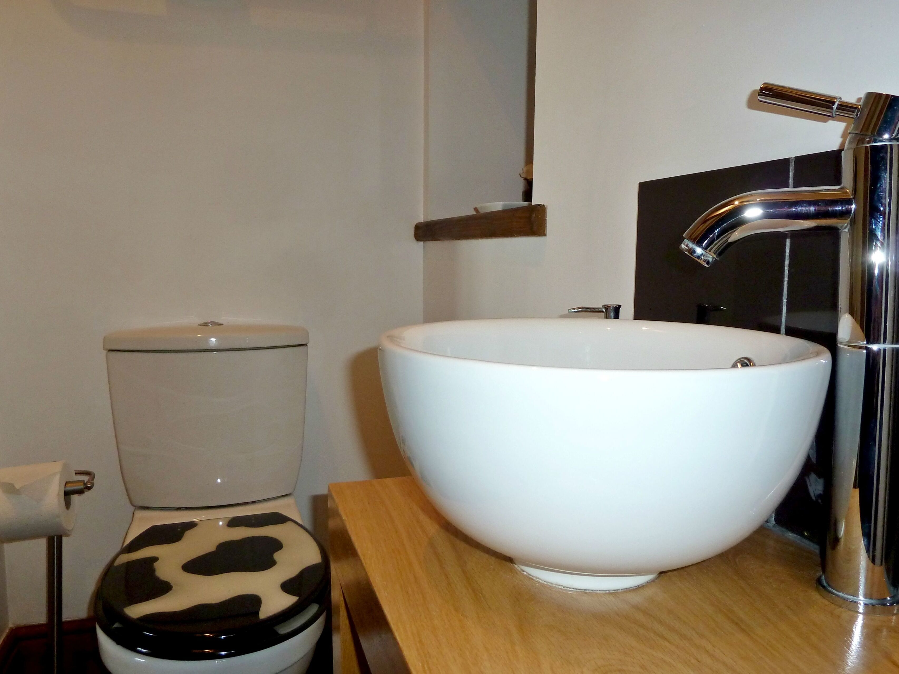 A bathroom with a toilet, a white sink, and a chrome faucet.