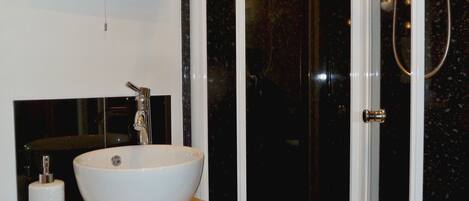 A bathroom with a white sink, a mirror, and a shower.