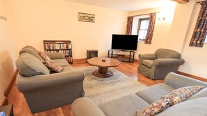 Un salon avec deux canapés gris, une table basse, une bibliothèque et un téléviseur à écran plat.