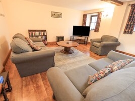 A living room with two grey sofas, a coffee table, a bookshelf, and a flat-screen TV.