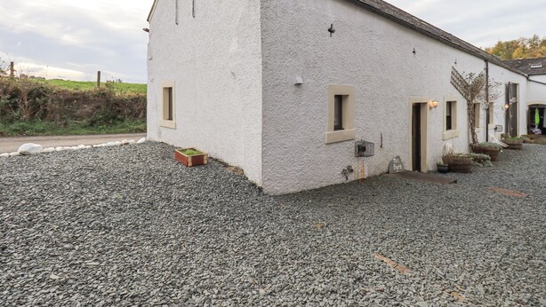 Un bâtiment blanc avec un toit en pente, une allée gravillonnée et une petite fenêtre.