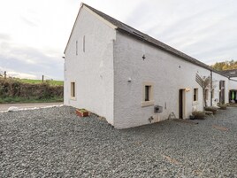 A white building with a sloped roof, a gravel driveway, and a small window.