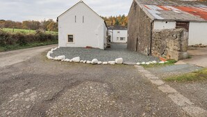 Un bâtiment situé en zone rurale, avec une allée en gravier et un mur en pierre.