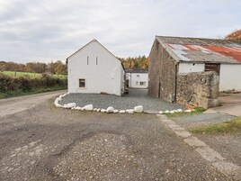 A rural building with a gravel driveway and a stone wall.