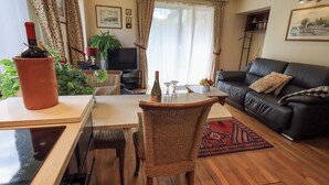 A living room with a dining table, a sofa, a TV, and a potted plant. - Stonegarth Cottage (Ambleside)