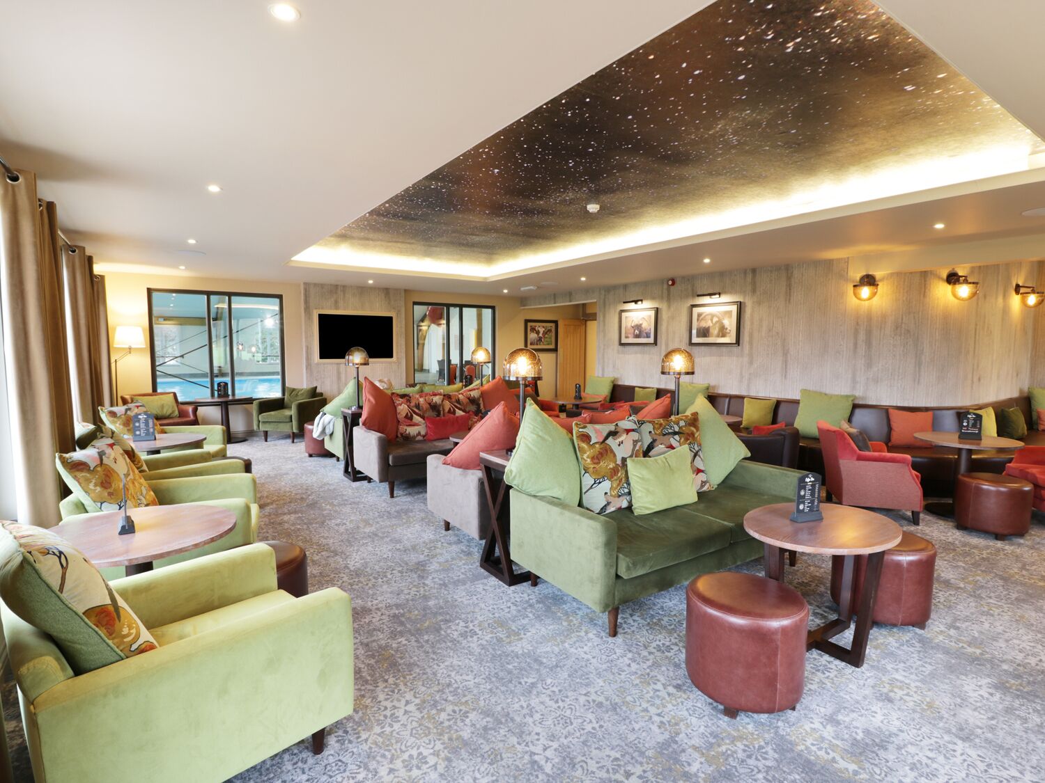 A spacious lounge area with multiple seating options including sofas and armchairs, a large flat-screen TV, and a decorative ceiling.
