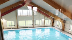 Ein Hallenbad mit hoher Decke und großen Fenstern.