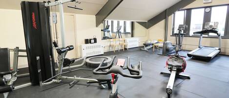 A gym with various exercise equipment, including a treadmill, stationary bikes, and weight machines.