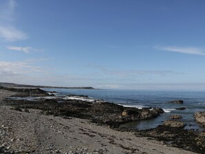 A rocky shoreline with waves crashing against the rocks under a clear sky.