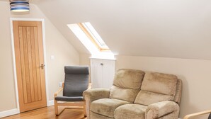 A cozy room with a beige sofa, a grey armchair, and a checkered rug. - Providence Apartment (Doncaster)
